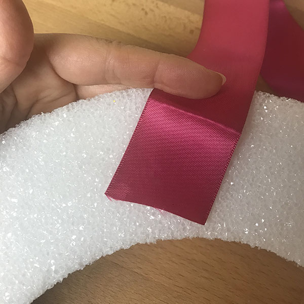 Attaching ribbon to wreath with hot glue
