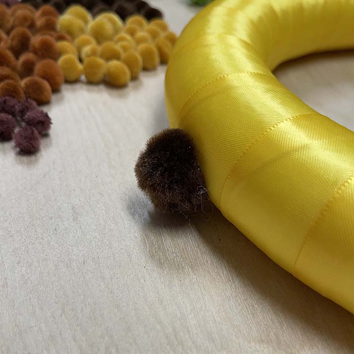 Adding pom poms to side of wreath