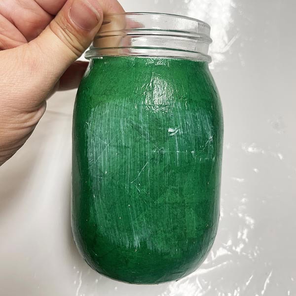 Brushing Mod Podge on front of jar
