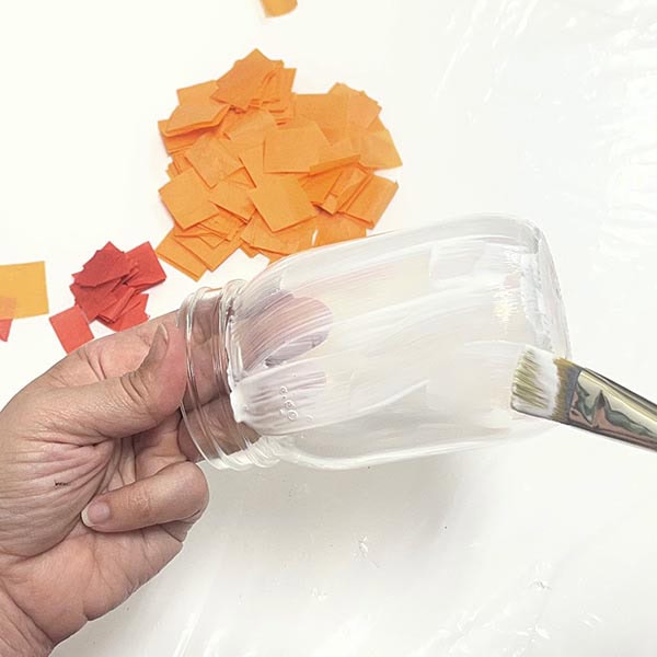 Brushing Mod Podge on mason jar